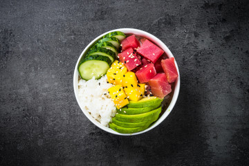 Tuna poke bowl on black background top view.