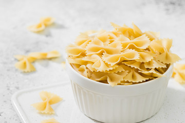 Farfalle pasta in a white bowl on a light background
