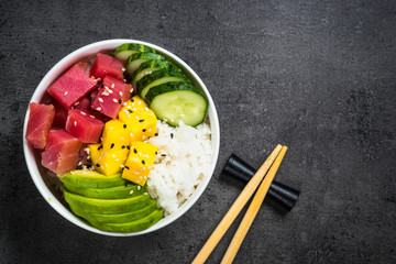 Tuna poke bowl on black background top view.