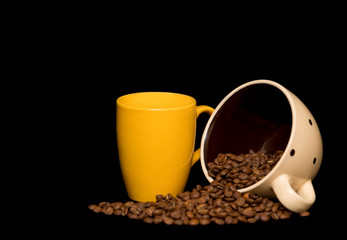 Coffee beans spread around coffee mugs on a black background
