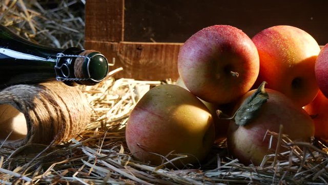 Moving camera slider showing bottle of cider with apples on the straw
