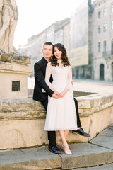 Chinese cute bride and groom young newlyweds just married couple posing on the stone stairs on streets of old city on wedding day.