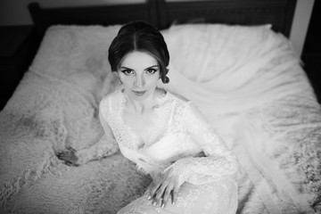 Gorgeous sensual bride portrait. Morning of the bride. Beautiful young woman in white negligee in the morning. Sensuality with beauty makeup and hair style. Black and white
