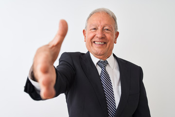 Senior grey-haired businessman wearing suit standing over isolated white background smiling friendly offering handshake as greeting and welcoming. Successful business.