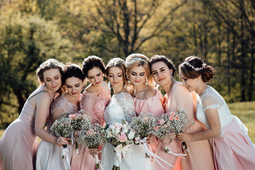 Group portrait of bride and bridesmaids. Stylish wedding in pink color. Marriage concept. Young bride and bridesmaids in pink dresses stand with wedding bouquets in the park - obrazy, fototapety, plakaty