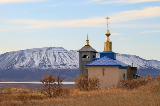 Autumn landscape with the Orthodox Church on a background of mountains. Russian Orthodox Church in the Far East. Church Of St. Nicholas, Urban-type settlement Beringovsky, Chukotka, Siberia, Russia.