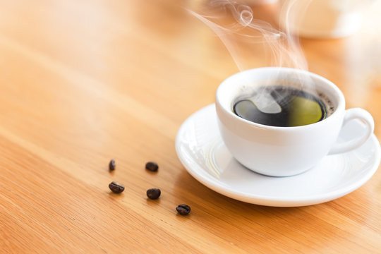 Hot coffee with smoke on the table in coffee shop