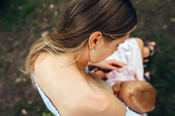 Mother breast feeding adorable baby child outdors. Closeup. Top view.