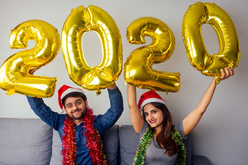 happy man beautiful and woman holding air ballons 2020 new year in living room at day light India