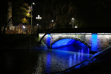 Riga park at night. Illuminated bridge over the river. Sightseeing tourist concept. Christmas lights.