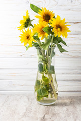 Beautiful yellow sun flowers in glass vase on the table. Minimalism style composition with copy space for your text. Template greeting card with beautiful flower.
