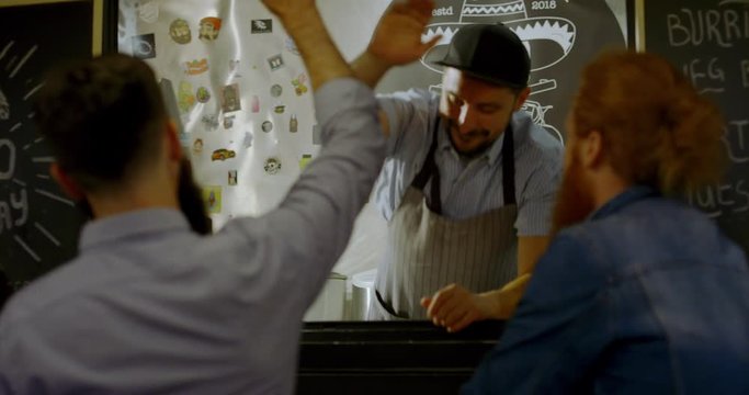 TRACKING Cheerful waiter taking order from customers at counter, Mexican street food served from a food truck. 4K UHD RAW graded footage