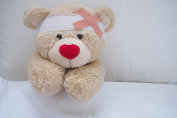Teddy bear with a wound dress, wound and broken hands. Sleeping in bed. Sickness of children
