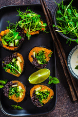 Vegan sushi rolls with black rice, avocado and sweet potato on black dish. Vegan food concept.