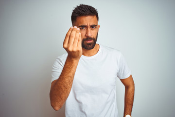 Young indian man wearing t-shirt standing over isolated white background Doing Italian gesture with hand and fingers confident expression