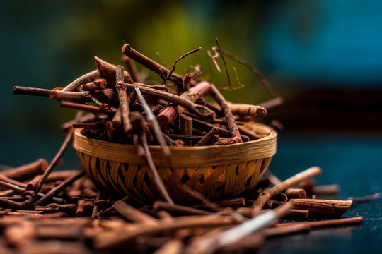 Bunch of Indian madderwort or madder root in a brown basket on the black surface also known as manjistha/manzistha/Rubia cordifolia/madder etc with its essential essence/concentration.Vertical shot.