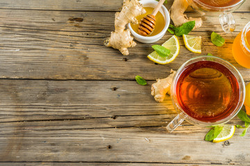 Autumn tea with mint and lemon with ingredients - fresh mint leaves, sliced lemon and honey, rustic wooden background copy space