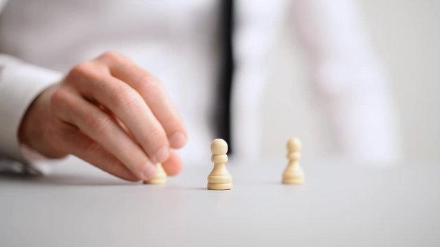 Hand of a businessman positioning chess pawn pieces in to a pyramid structure
