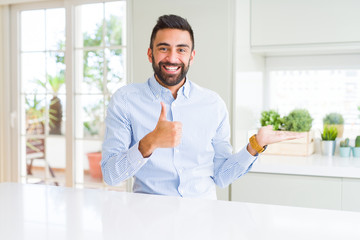 Handsome hispanic business man Showing palm hand and doing ok gesture with thumbs up, smiling happy and cheerful