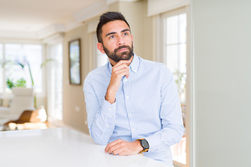 Handsome hispanic business man with hand on chin thinking about question, pensive expression. Smiling with thoughtful face. Doubt concept.