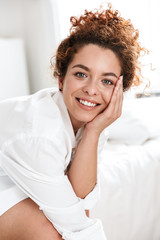 Cheerful woman in white shirt in home hotel on bed.