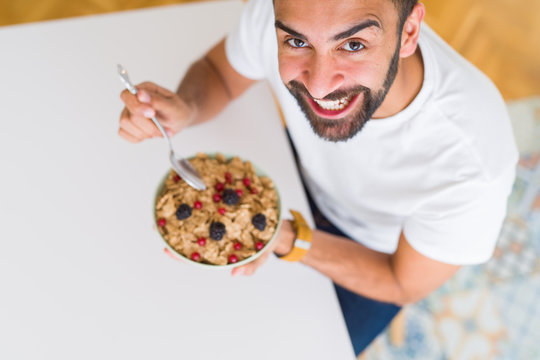 Above angle of handsome man eating healthy cereals for breakfast in the morning