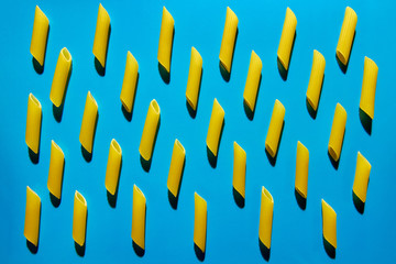 Yellow pasta on a blue background in hard light. Flat lay from macaroni
