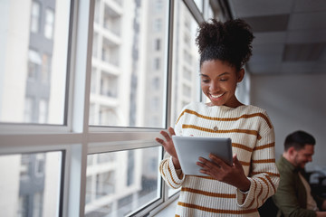 Smiling Brazilian female executive using a digital tablet in a modern architectural setting set in...