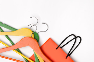 Orange paper shopping bag with colorful hangers over white background