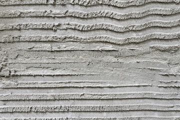 Rough grooved gray textured cement wall with pattern prepared for laying tile. Closeup