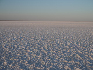 white surface of the lake covered with salt at sunrise