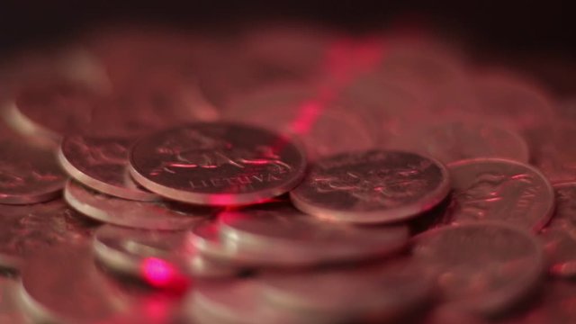 Close Up Of Rotating Lithuanian Aluminum Cent Coins Illuminated By Red Laser Light,