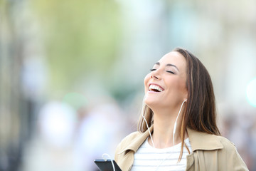 Happy woman listening to music breathing in the street