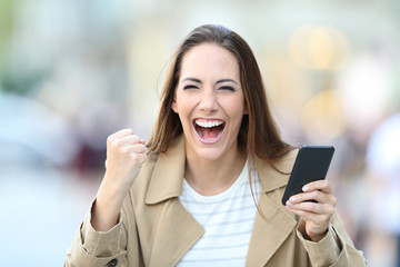 Excited woman holding phone looking at camera