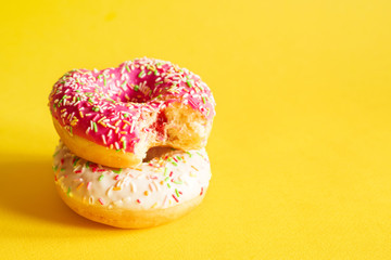 Two colorful donuts on yellow background, closeup