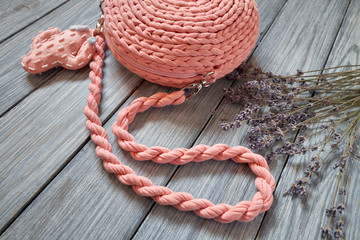 Handmade crochet pink bag with long handle, fittings and decorative stitched cactus on the blue wooden background with lavender flowers. Closeup, selective focus