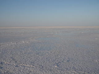 white surface of the lake covered with salt at sunrise