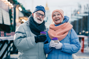 Happy aged couple being on the winter fair and smiling