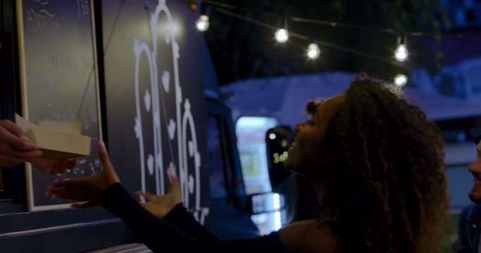 HANDHELD Cheerful waiter taking serving food to customers at counter, Mexican street food truck. 4K UHD RAW graded footage