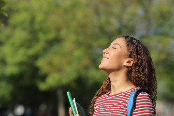 Happy mixed race student breathing fresh air in a park