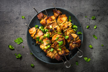 Grilled meat with herbs on black top view.