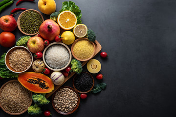 Obraz na płótnie Canvas Bunch of fresh seasonal fruits, vegetables and grains of legumes on a black background