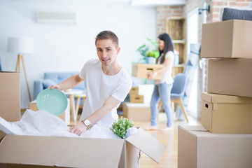 Young beautiful couple open cardboard boxes to order new home