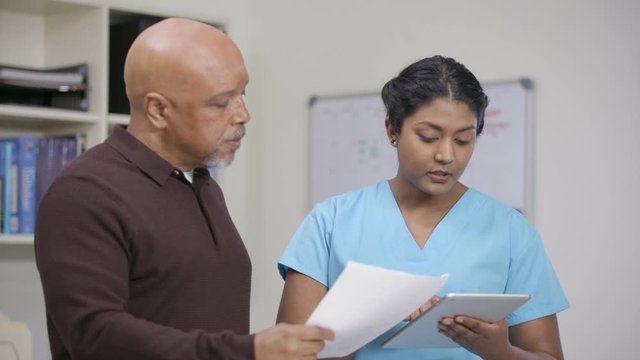 Nurse explains info on tablet and printout to family, slight camera move right