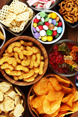 Salty snacks. Pretzels, chips, crackers and candy sweets on table