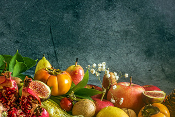 Ripe fruits, persimmons, apples, pears figs, nuts, melon, pomegranate on a dark background. Still life of autumn fruits, harvest concept. Nature background made of autumn fruit Autumn fruits concept
