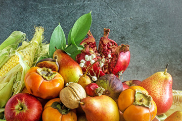 Ripe fruits, persimmons, apples, pears figs, nuts, melon, pomegranate on a dark background. Still life of autumn fruits, harvest concept. Nature background made of autumn fruit Autumn fruits concept