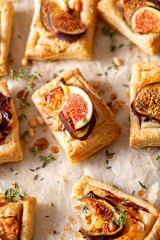 puff pastry tarts with figs, cheese, honey, nuts and thyme on parchment paper. selective focus
