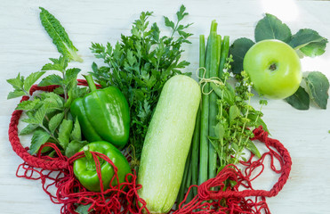 Red string bag full of green vegetables and fruit