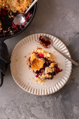 homemade plum crumble on white plate. top view